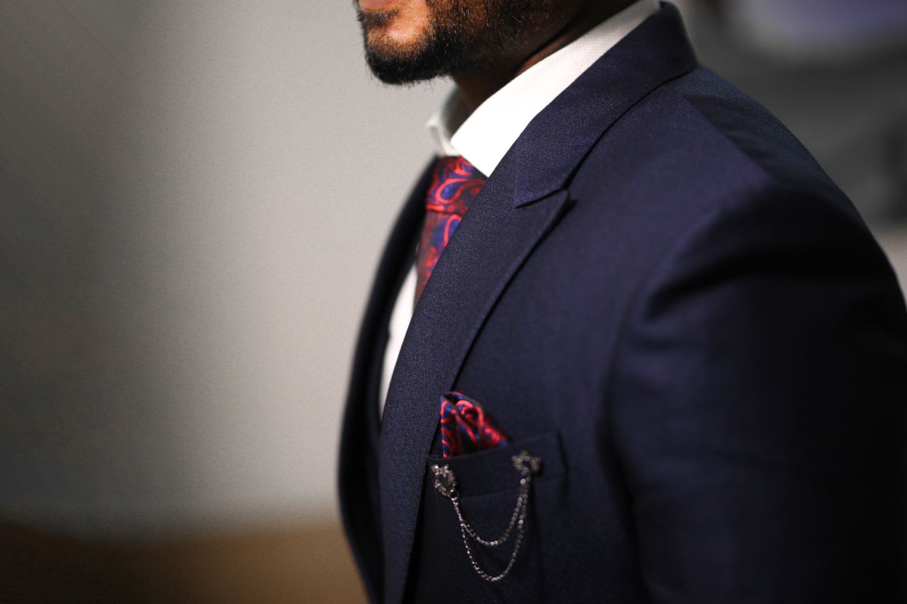 services-02 Close-up of a man in a navy suit with a stylish red tie and pocket square.
