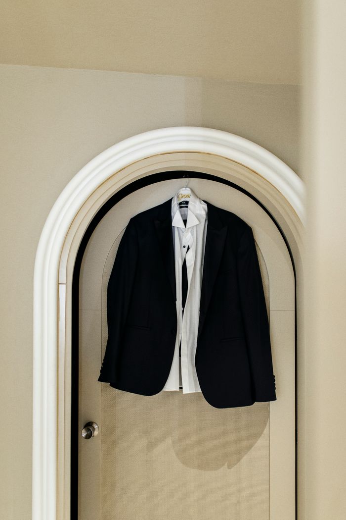 services-01 Classic black suit and white shirt hanging on an arched door, showcasing elegance and sophistication.